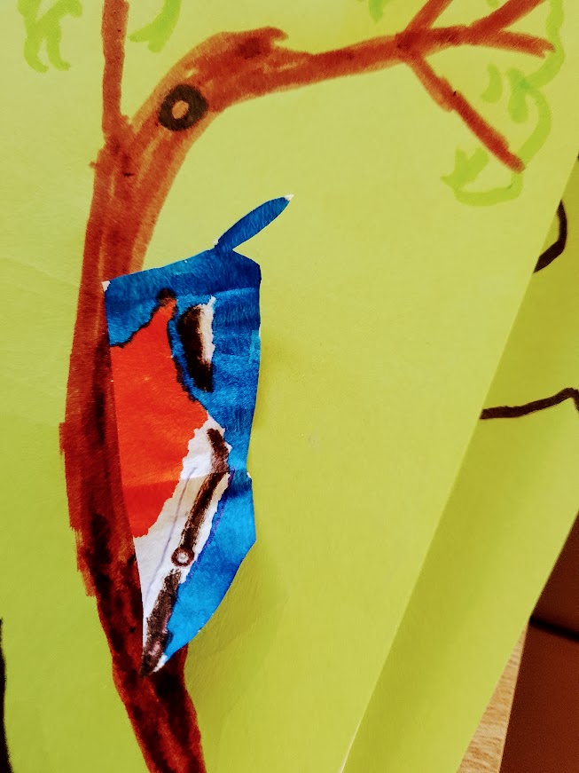 Kowalik z paska papieru na gałęzi głową w dół