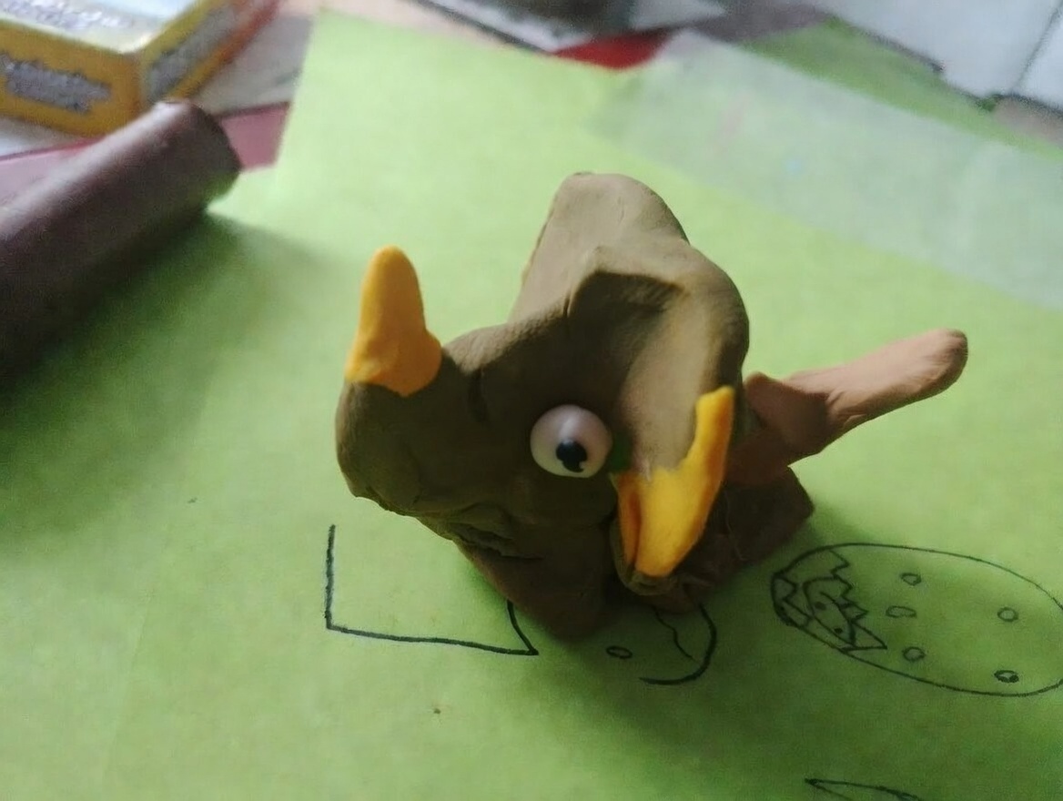 Kolorowe triceratopsy z plasteliny – żółty i niebieski w tle